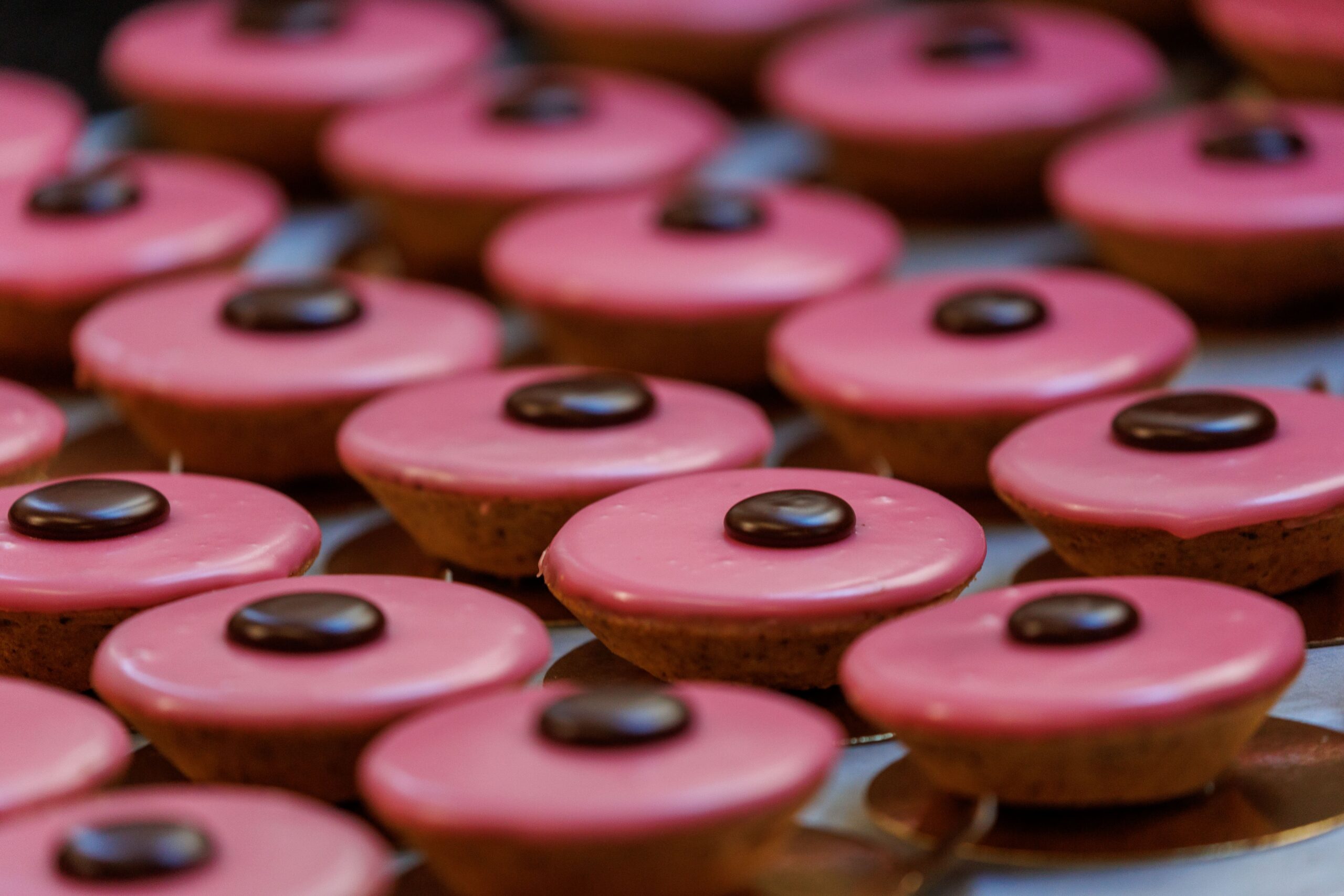 Des caracs au glaçage rose, ornés d’un rond de chocolat au centre.